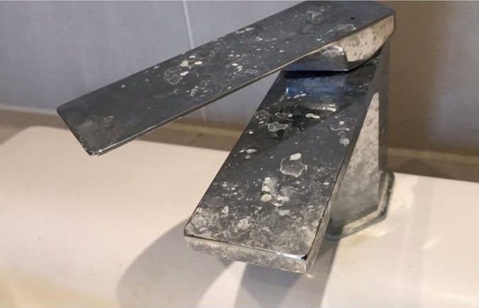 Bathroom faucet before cleaning, covered in limescale